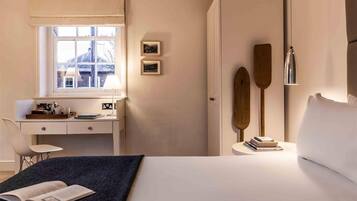 Un dormitorio con cama, escritorio, silla, ventana y armario.