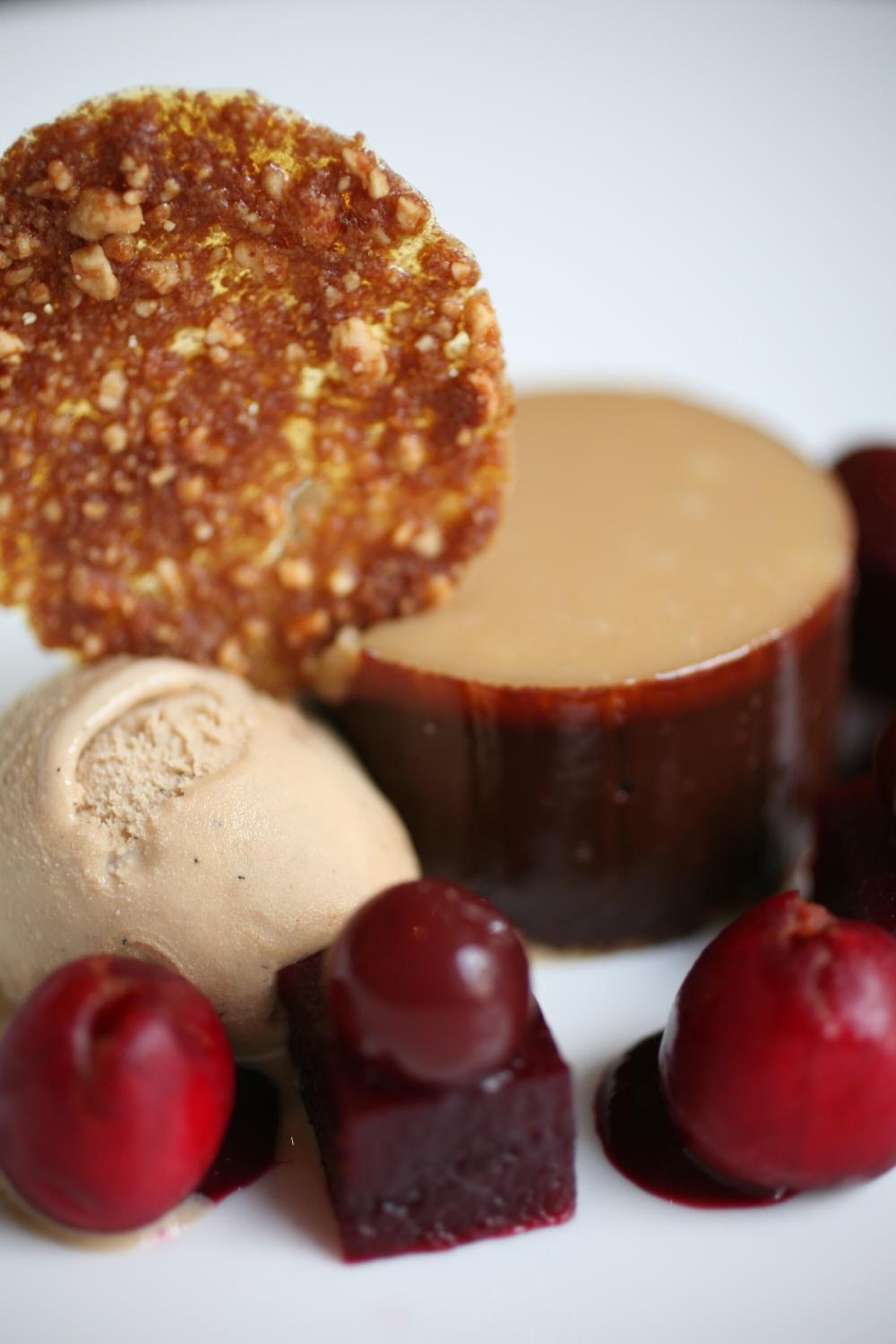 Um prato de sobremesa com um pudim de caramelo, uma bola de sorvete e pedaços de fruta.