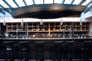 A bar area with a wooden ceiling, shelves of bottles, and bar stools. - The Crown hotel (Woodbridge)