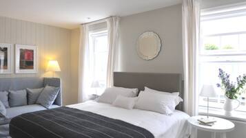 A hotel room with a bed, a sofa, a small table, a lamp, and a window with curtains.