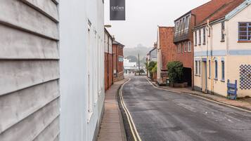 A narrow street lined with buildings, including a pub named "The Crown Woodbridge."