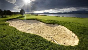 A golf course with a sand bunker, a flag, and a lake in the background. - Isle of Eriska Hotel and Spa (Oban)