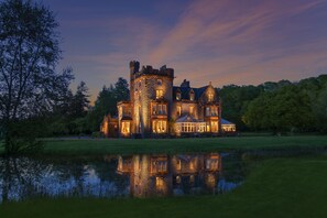 A large, castle-like building with multiple towers and a reflective pond in front.