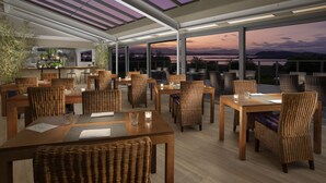 A restaurant with outdoor seating, large windows, and a view of the water. - Isle of Eriska Hotel and Spa (Oban)