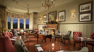 A formal dining room with a fireplace, elegant chairs, and a chandelier.
