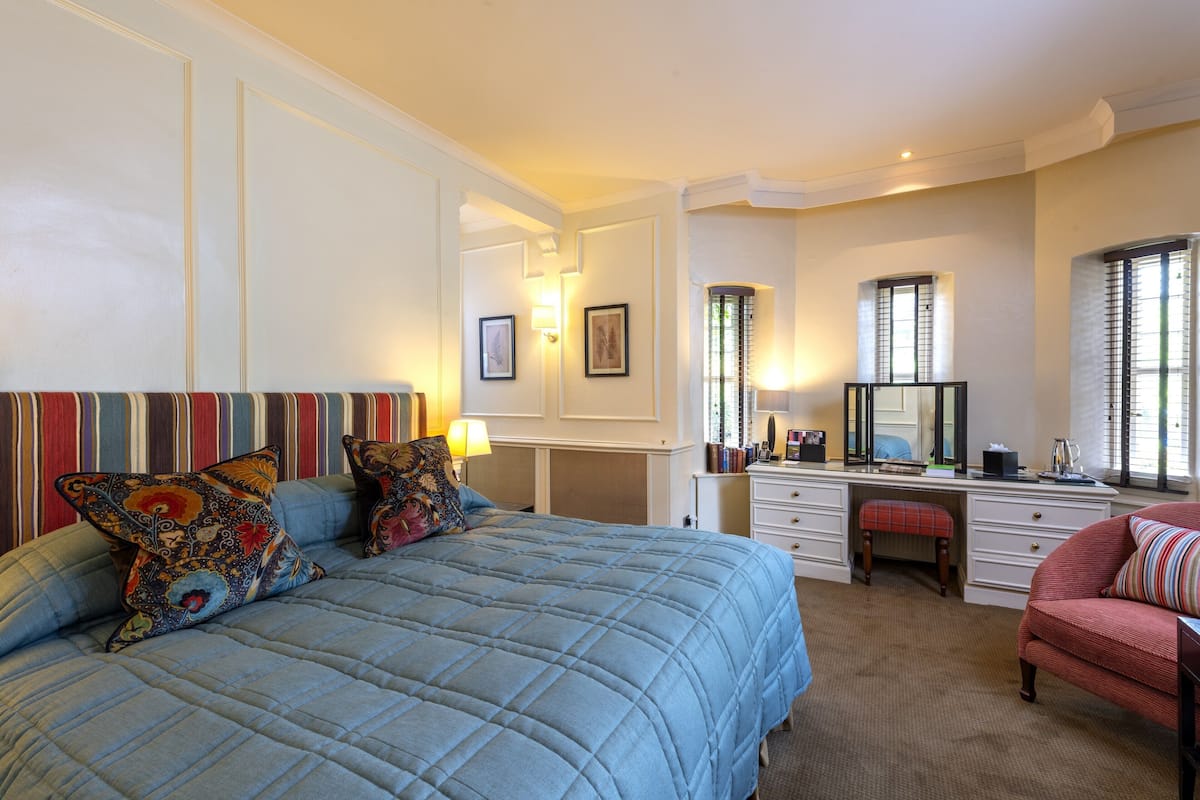 A bedroom with a large bed, a desk, a chair, and a dresser.