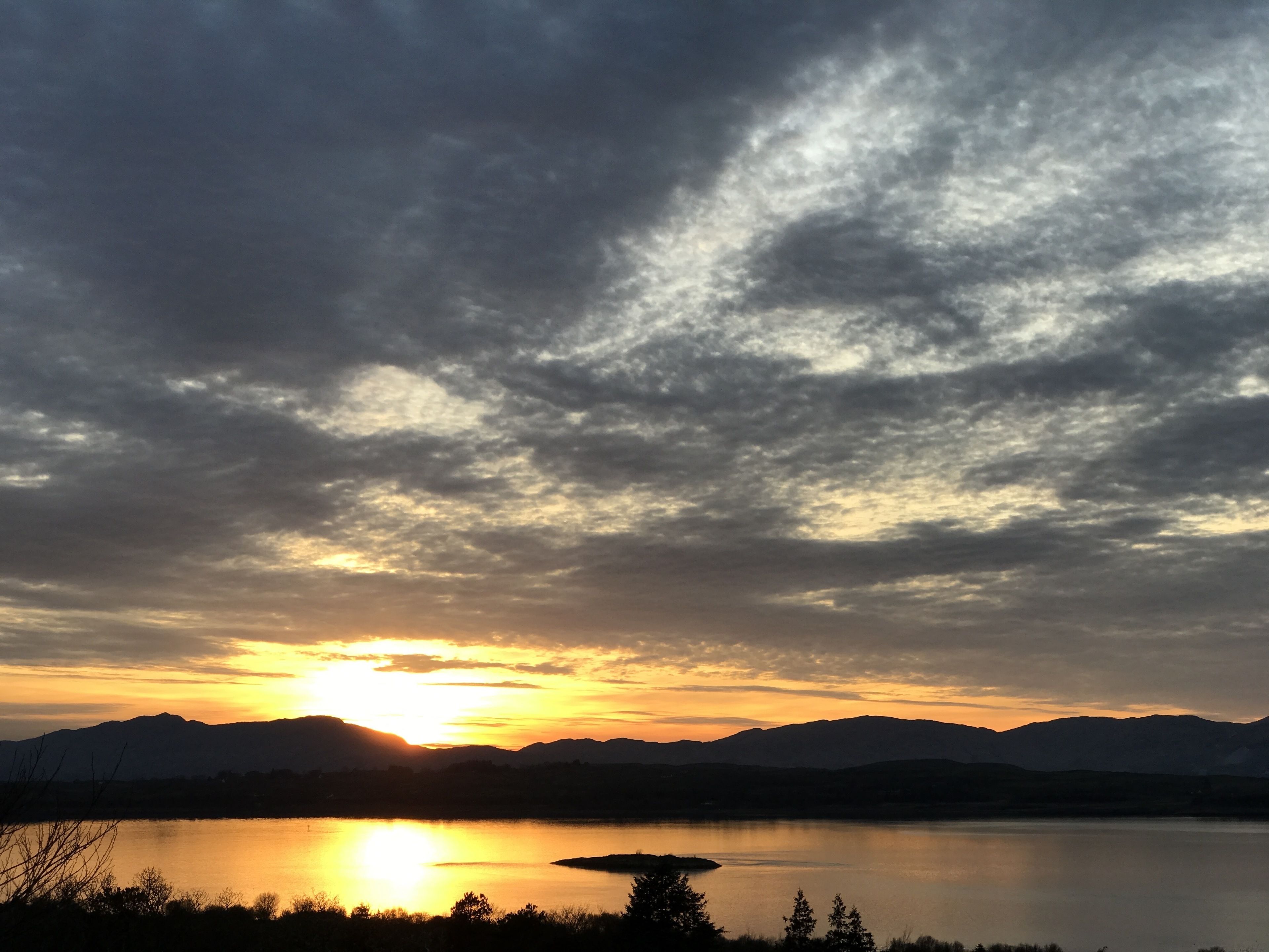 A sunset over a lake with mountains in the background.