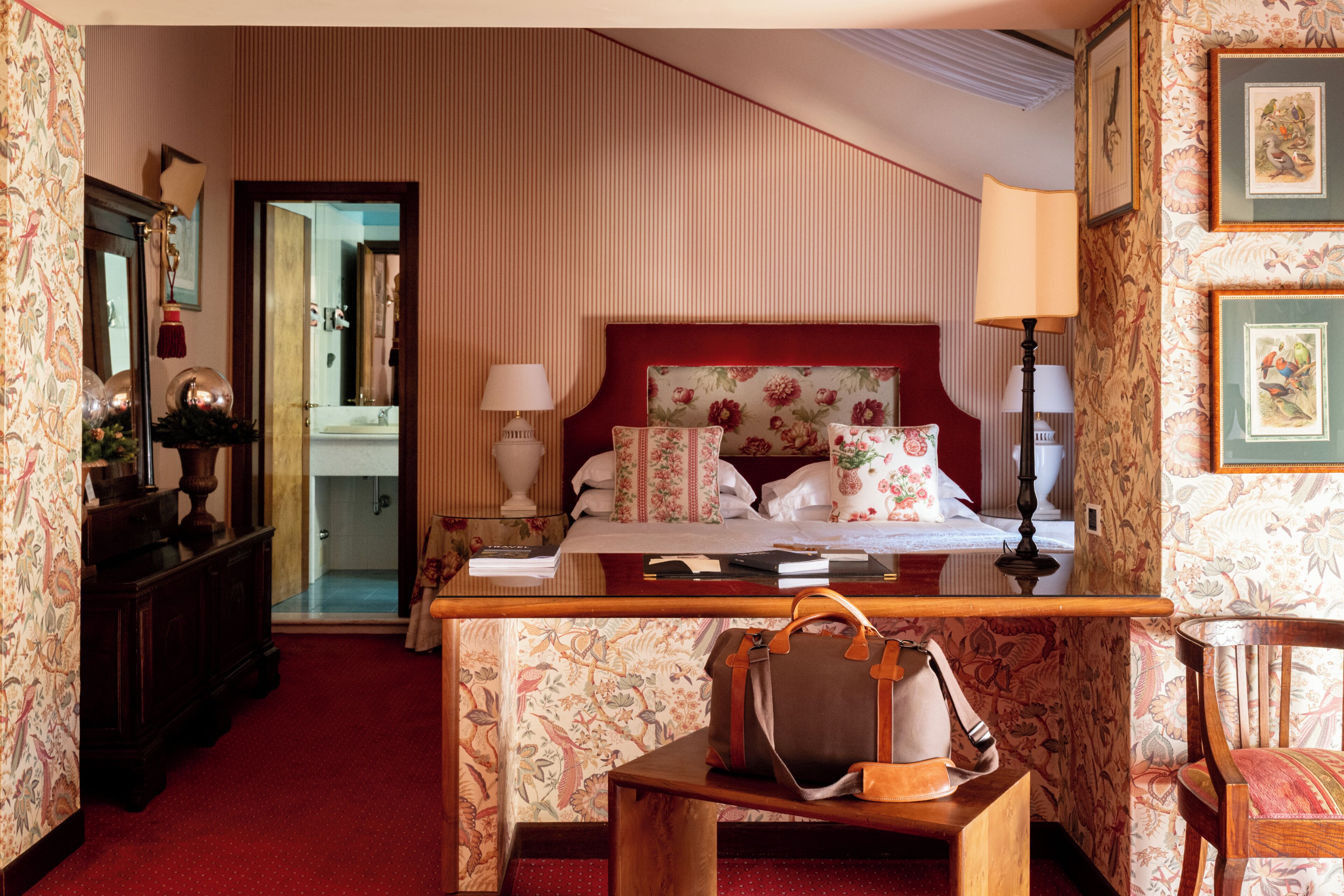 A hotel room with a bed, bedside table, lamp, and a view of the bathroom.