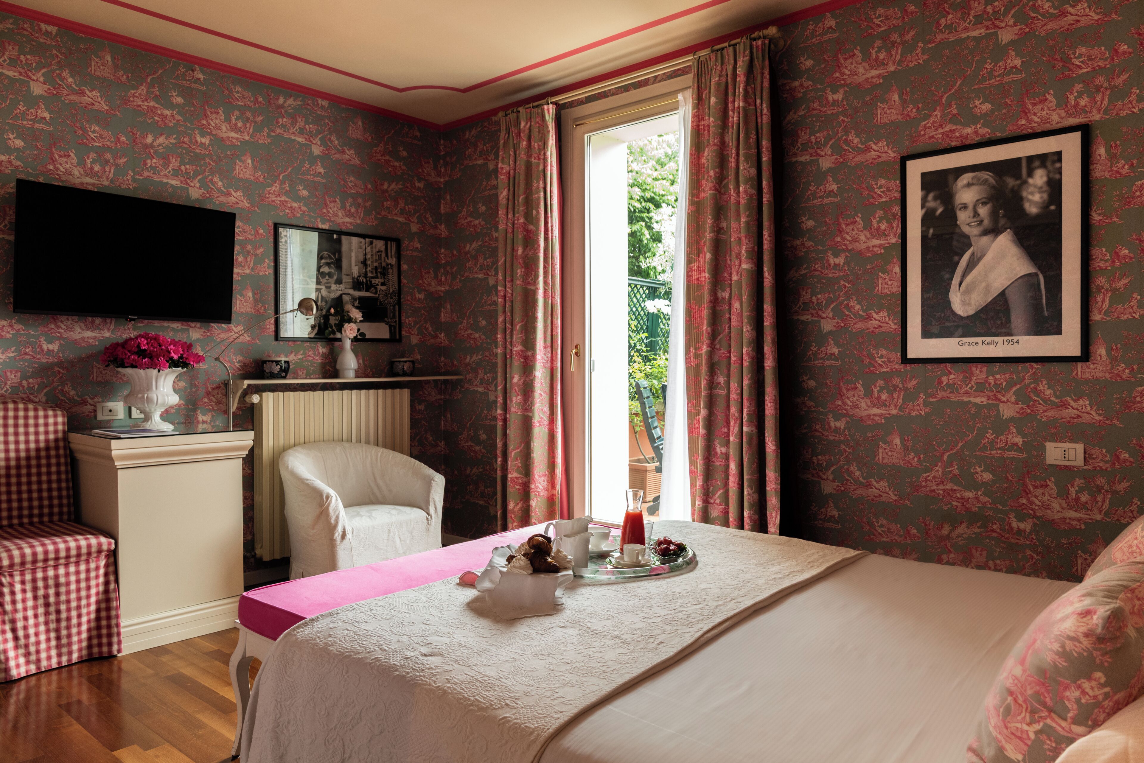 Une chambre à coucher comprenant un lit, un bureau, une chaise, un téléviseur et une fenêtre avec des rideaux.