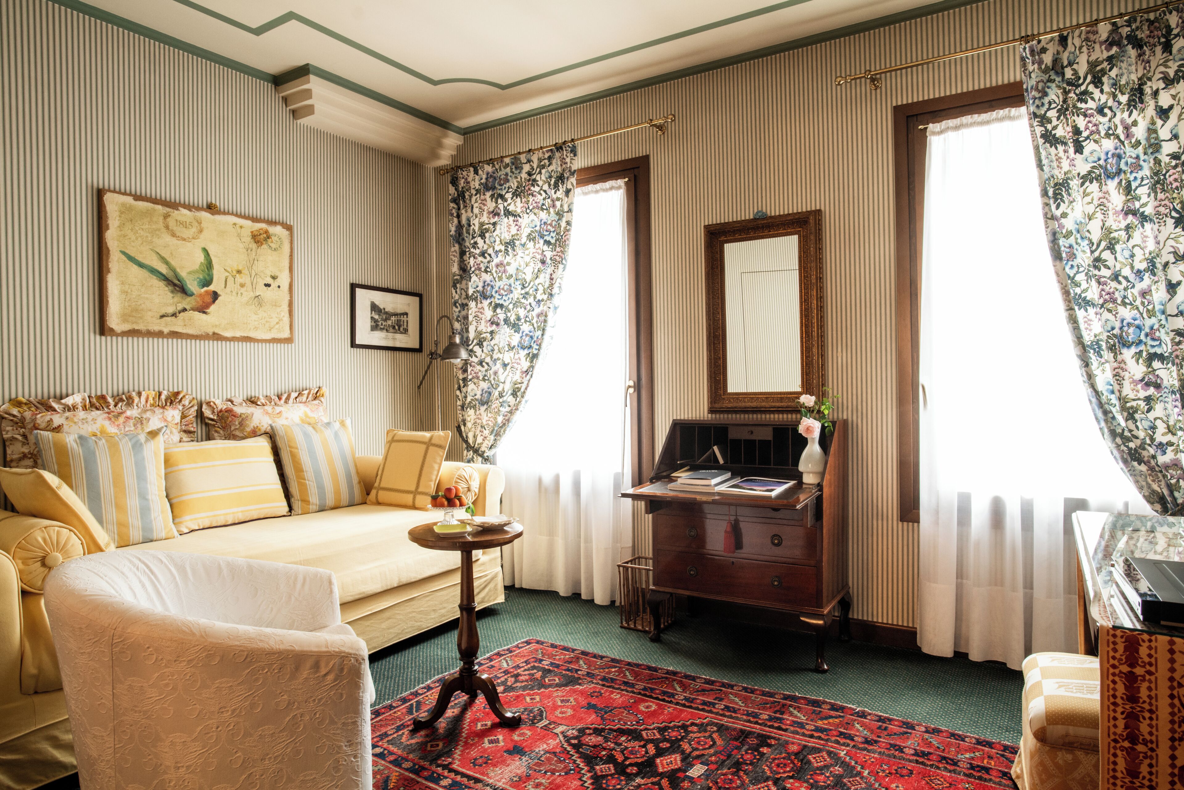 Une pièce comprenant un canapé, une petite table, un miroir et un tapis à motifs.