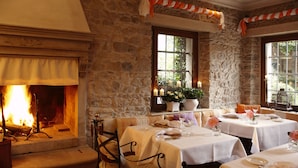 A cozy restaurant with stone walls, a fireplace, and tables set for dining. - Relais & Chateaux Villa Abbazia (Follina)