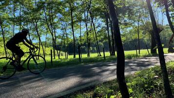 A cyclist on a paved path surrounded by trees and greenery.