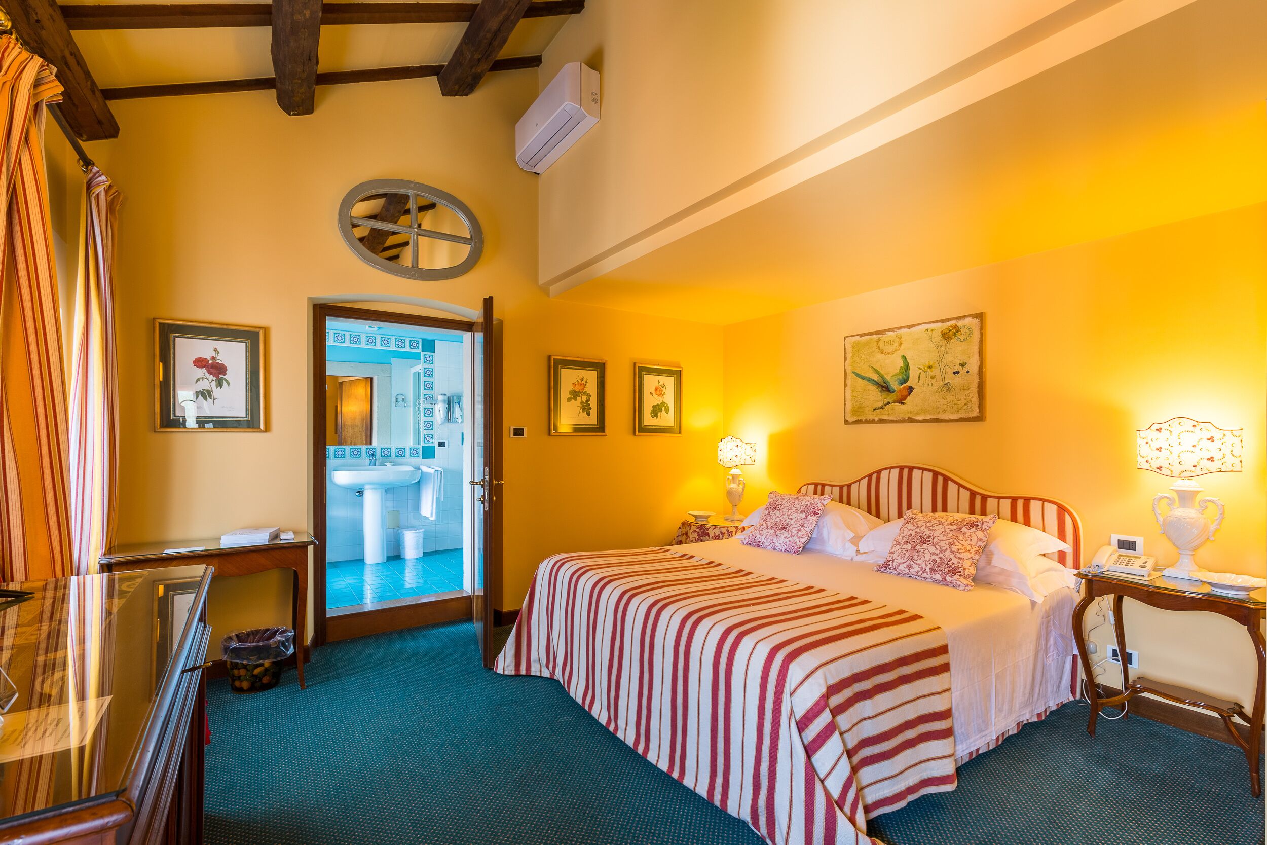 A hotel room with a bed, bedside table, lamp, and a view of the bathroom.