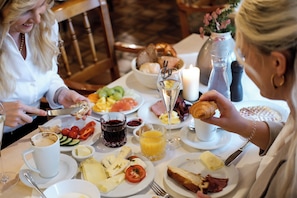 A dining table with plates of food, a glass of orange juice, and a candle. - Romantik Hotel Hirschen (Parsberg)