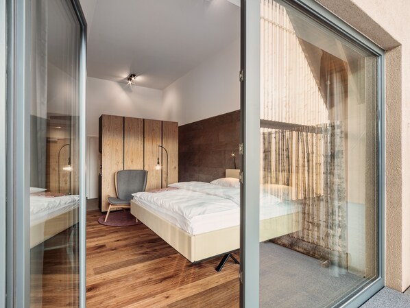 A modern bedroom with a large bed, a chair, and a wooden wardrobe.