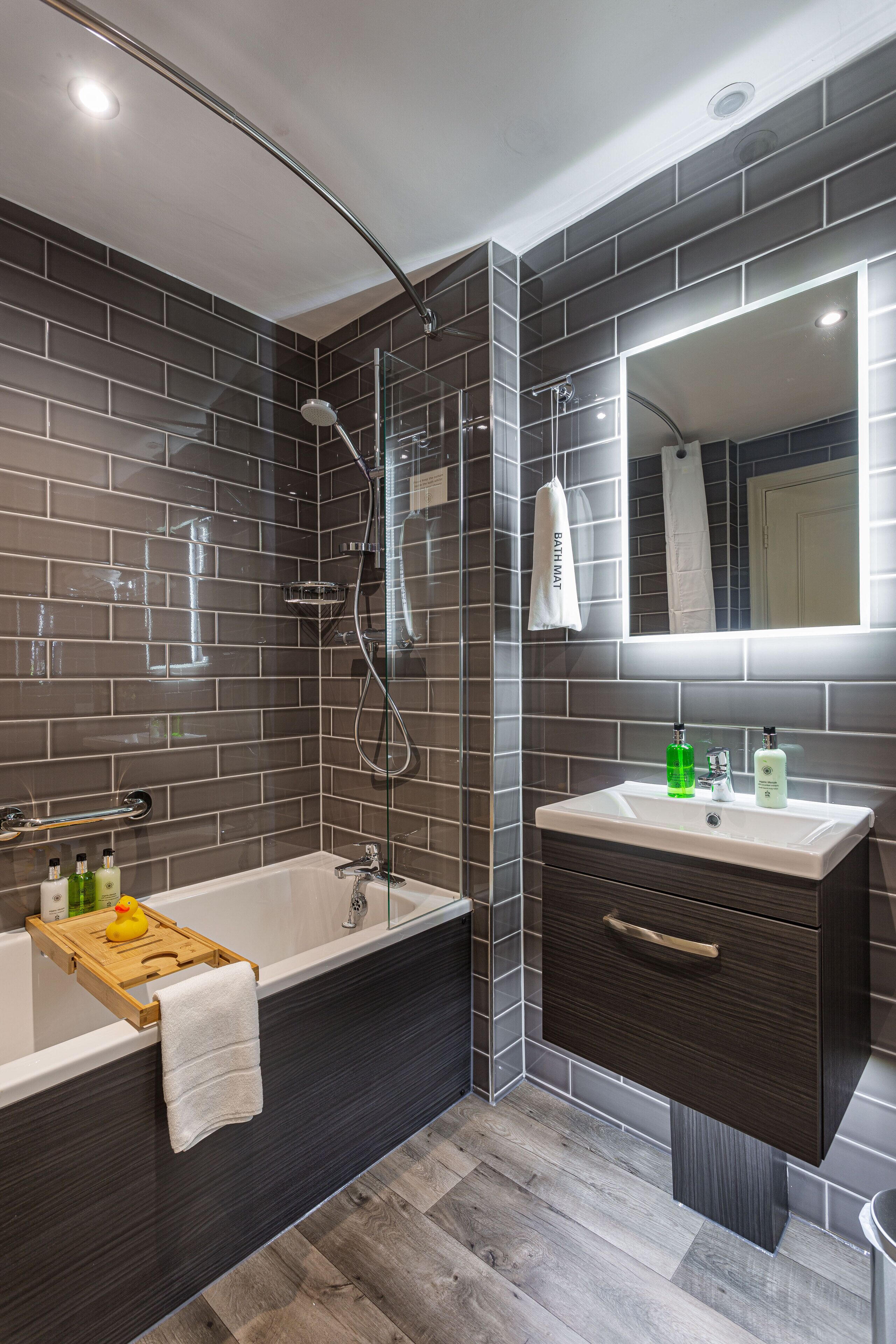 A modern bathroom with a bathtub, a vanity with a mirror, and a shower area.
