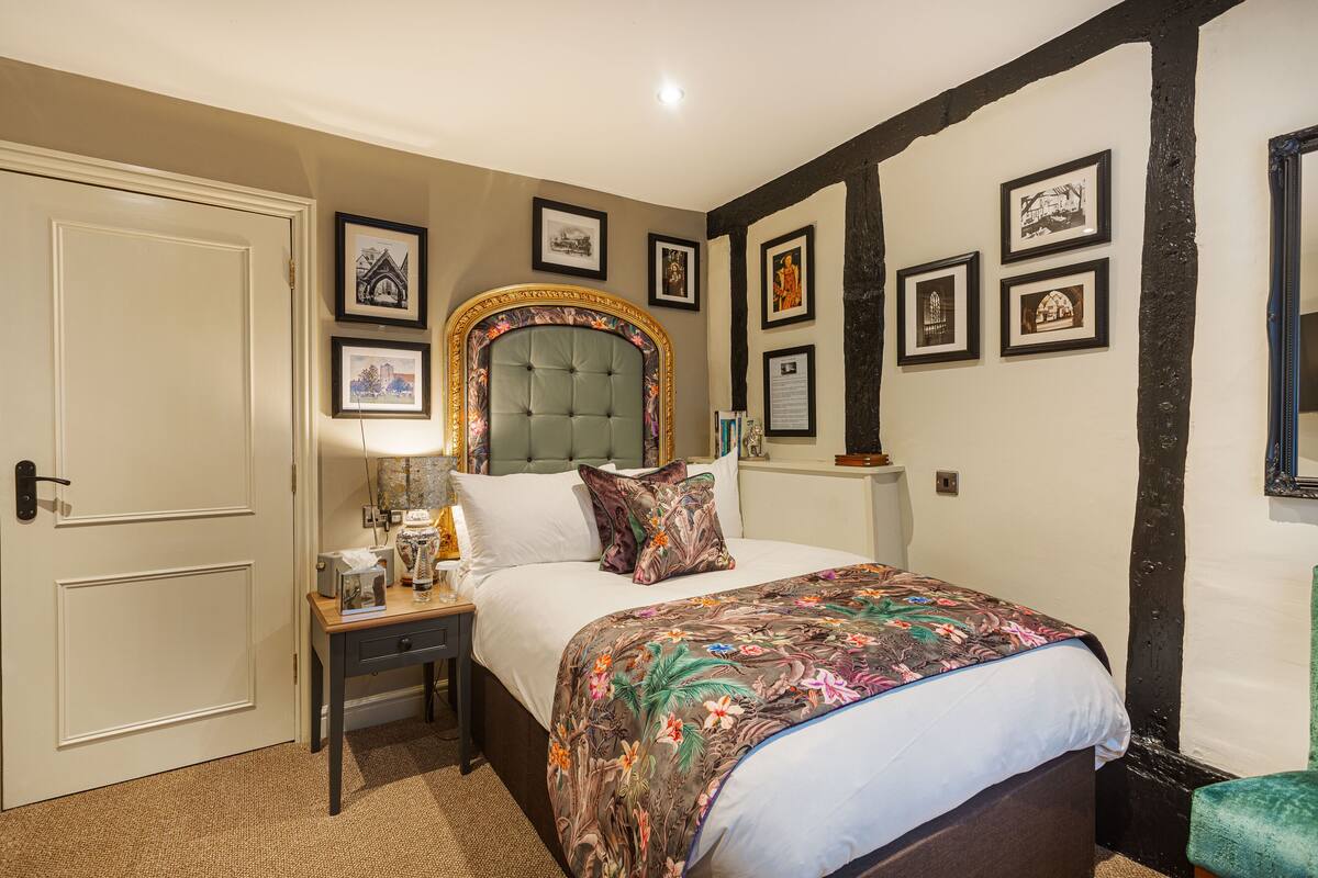 A bedroom with a large bed, a nightstand, a dresser, and a door.