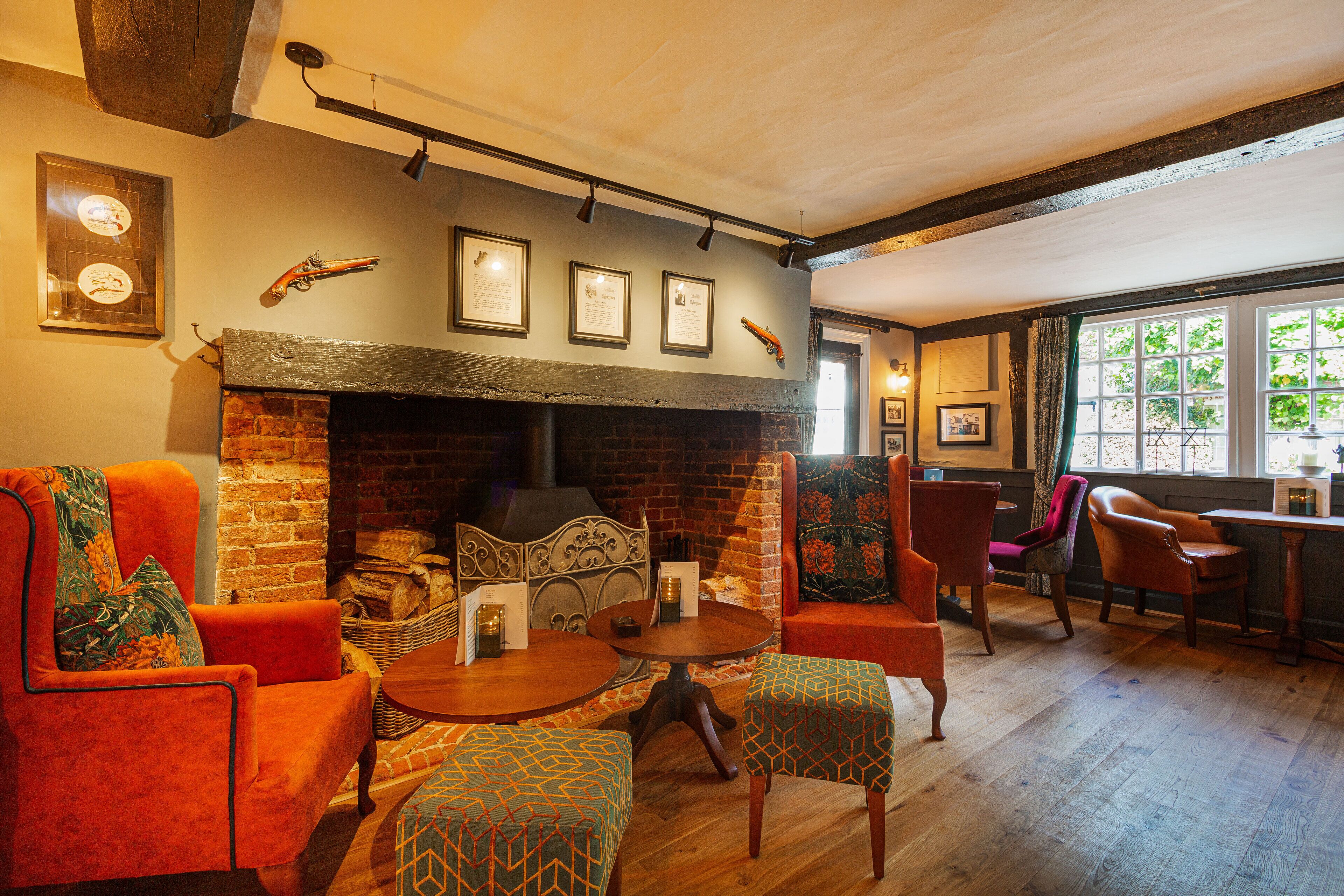 A cozy room with a brick fireplace, comfortable seating, and framed pictures on the wall.