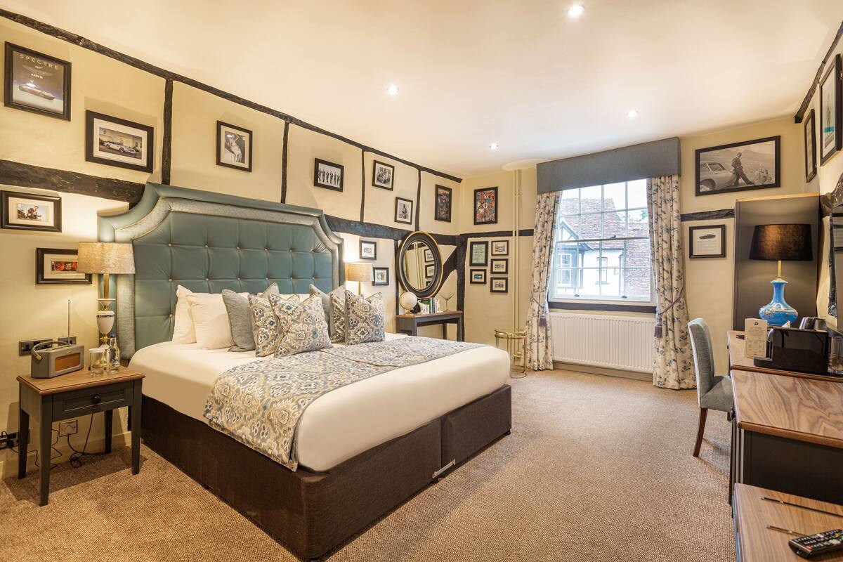 A neatly arranged bedroom with a large bed, bedside tables, a desk, and a chair.