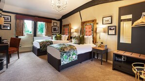 A hotel room with a large bed, a desk, a chair, a small table, and a mirror.