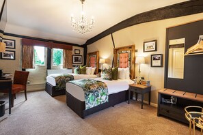 A hotel room with a large bed, a desk, a chair, a small table, and a mirror.