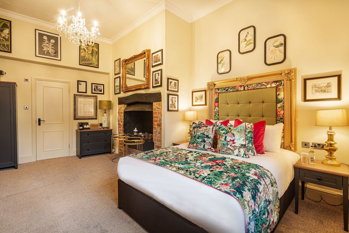 A well-appointed bedroom with a large bed, a fireplace, and a chandelier.
