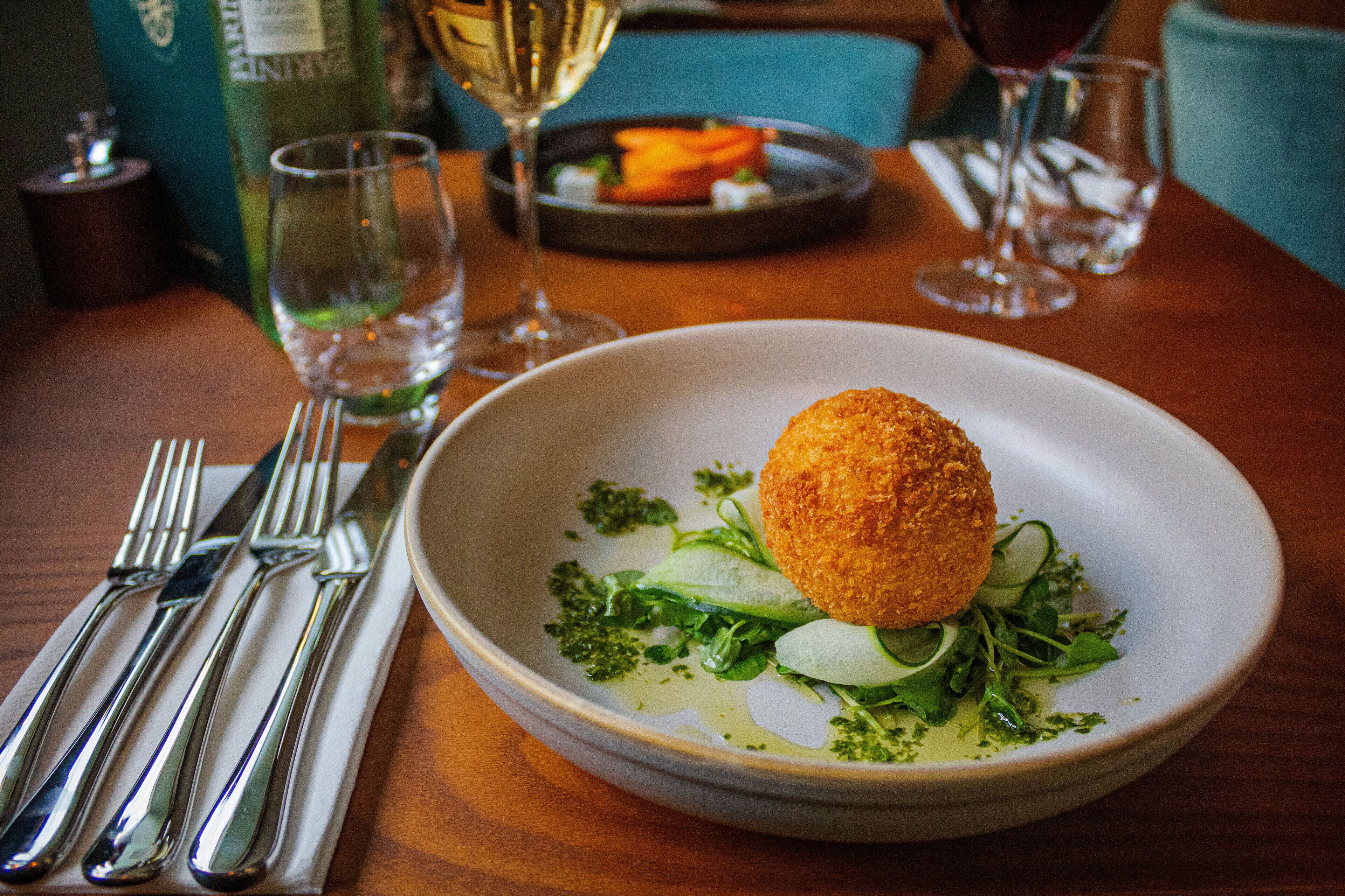 Une table à manger avec une assiette de nourriture, un verre de vin et une bouteille de vin.