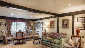 A traditional room with a green sofa, two armchairs, a coffee table, and a lamp.