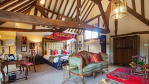 A traditional room with a bed, a green sofa, a red carpet, and wooden beams on the ceiling. - The George Hotel, Dorchester-on-Thames (Wallingford)