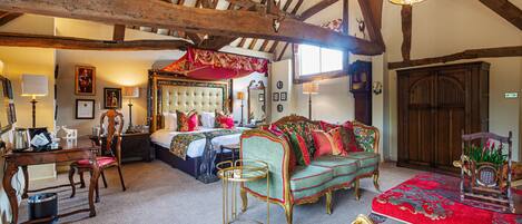 A traditional room with a bed, a green sofa, a red carpet, and wooden beams on the ceiling.