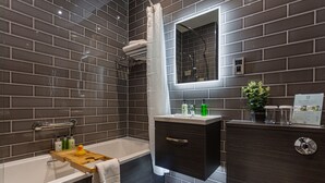 A modern bathroom with a bathtub, a vanity with a mirror, and a toilet.