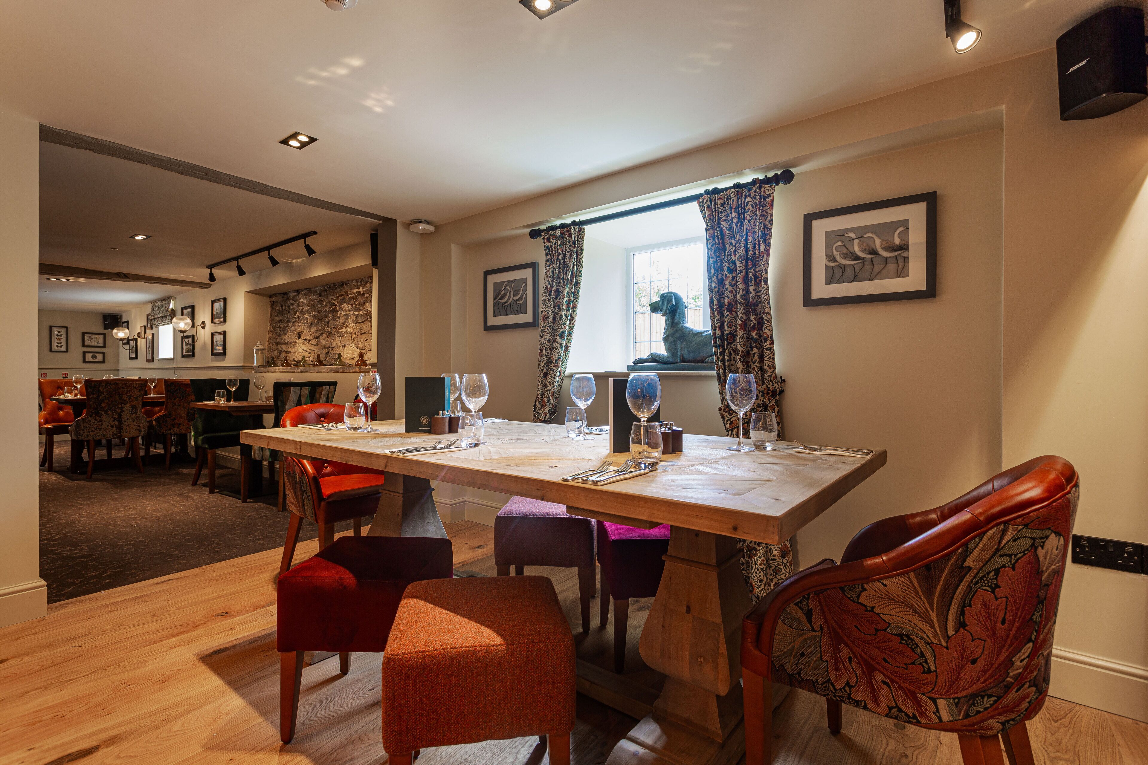 Un coin repas avec une table en bois dressée pour quatre personnes, entourée de chaises rembourrées.