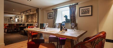 Comedor con una mesa de madera dispuesta para cuatro personas, rodeado de sillas tapizadas.
