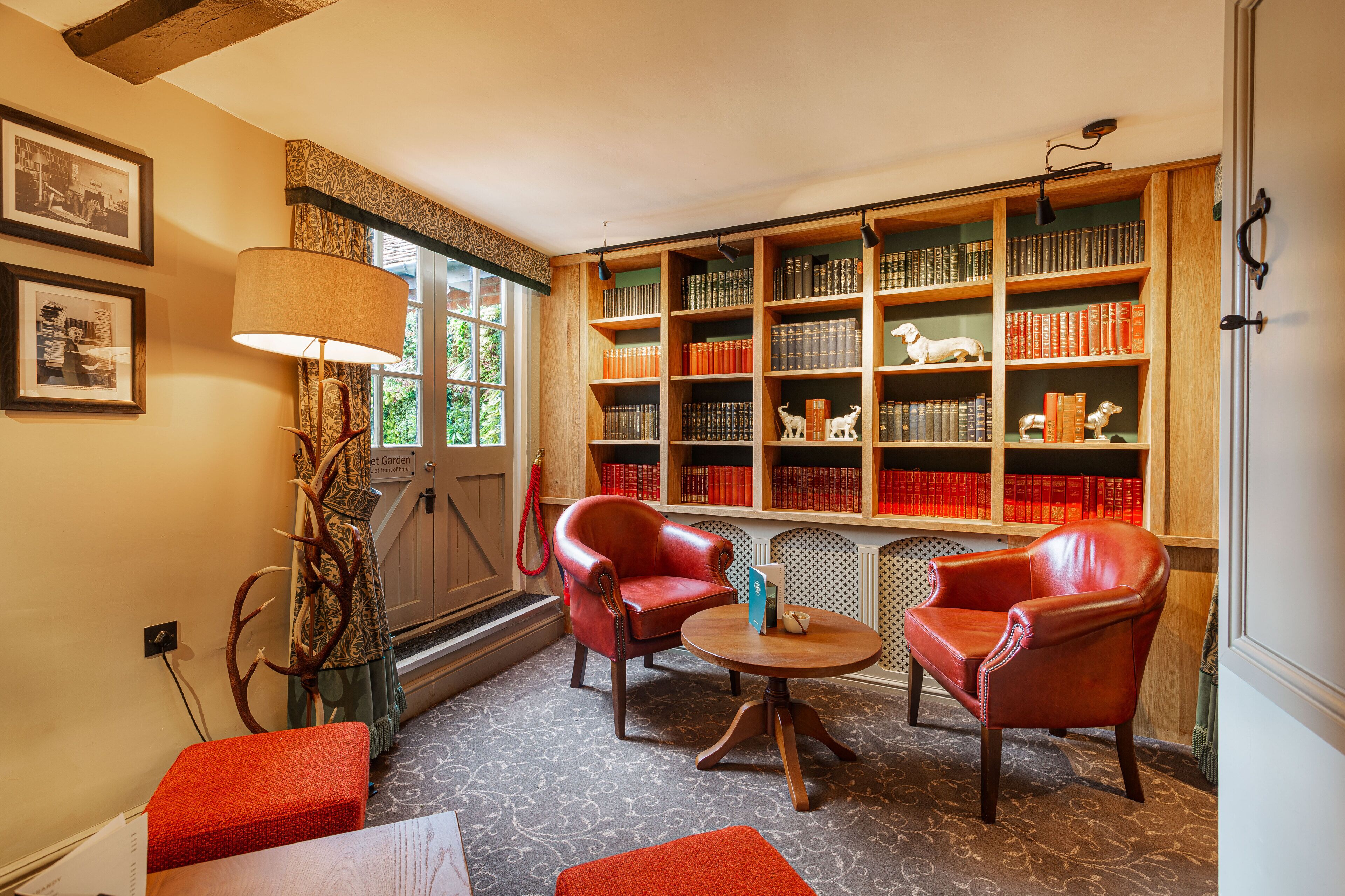 A library with leather chairs, bookshelves, and a lamp.