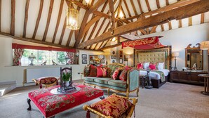 A traditional room with a high ceiling, a bed with ornate headboard, a red and gold patterned sofa, and a wooden floor. - The George Hotel, Dorchester-on-Thames (Wallingford)