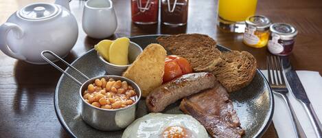Un plato de desayuno con huevos, frijoles, tostadas, salchichas y tocino.