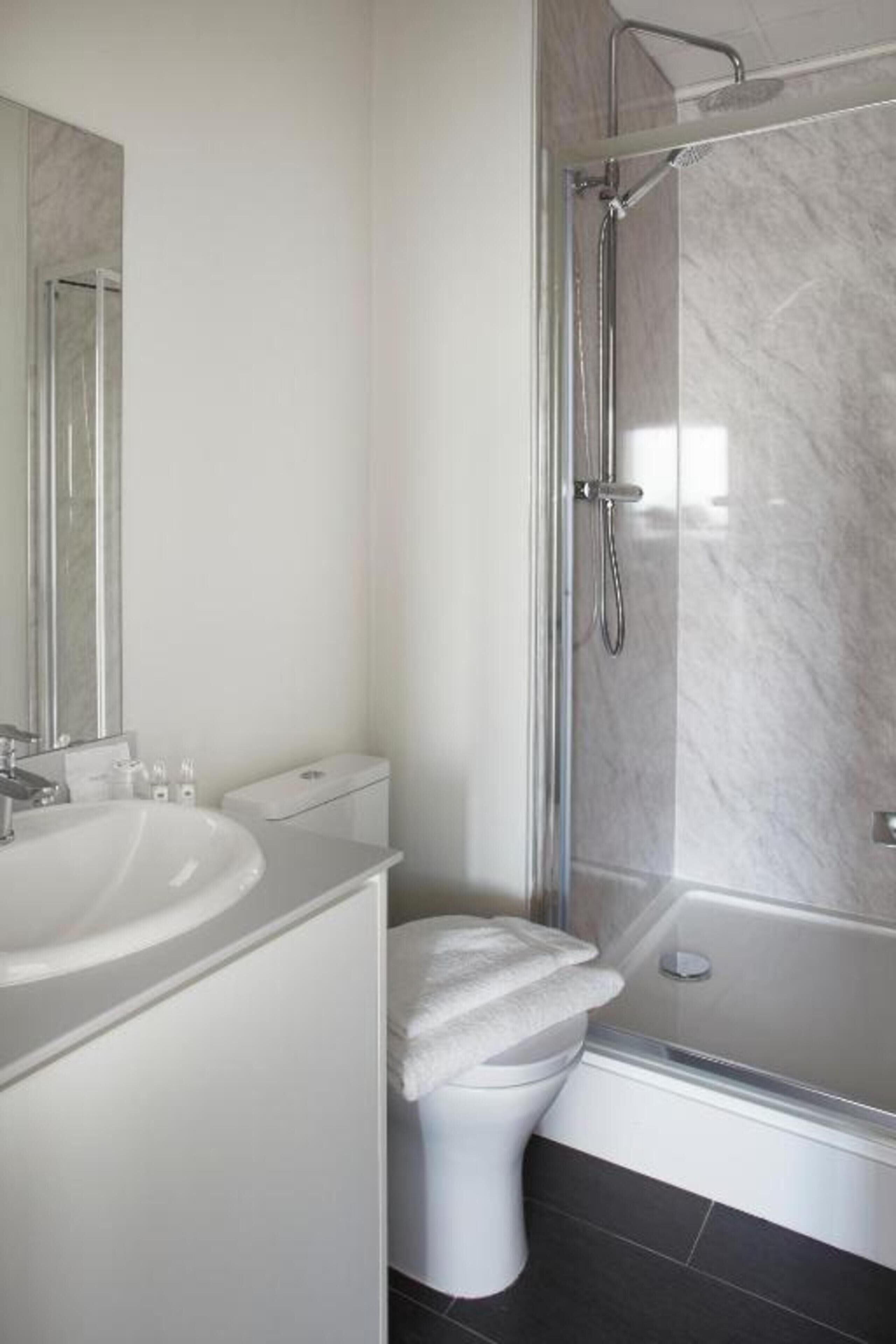 A modern bathroom with a glass-enclosed shower, a white sink, and a toilet.