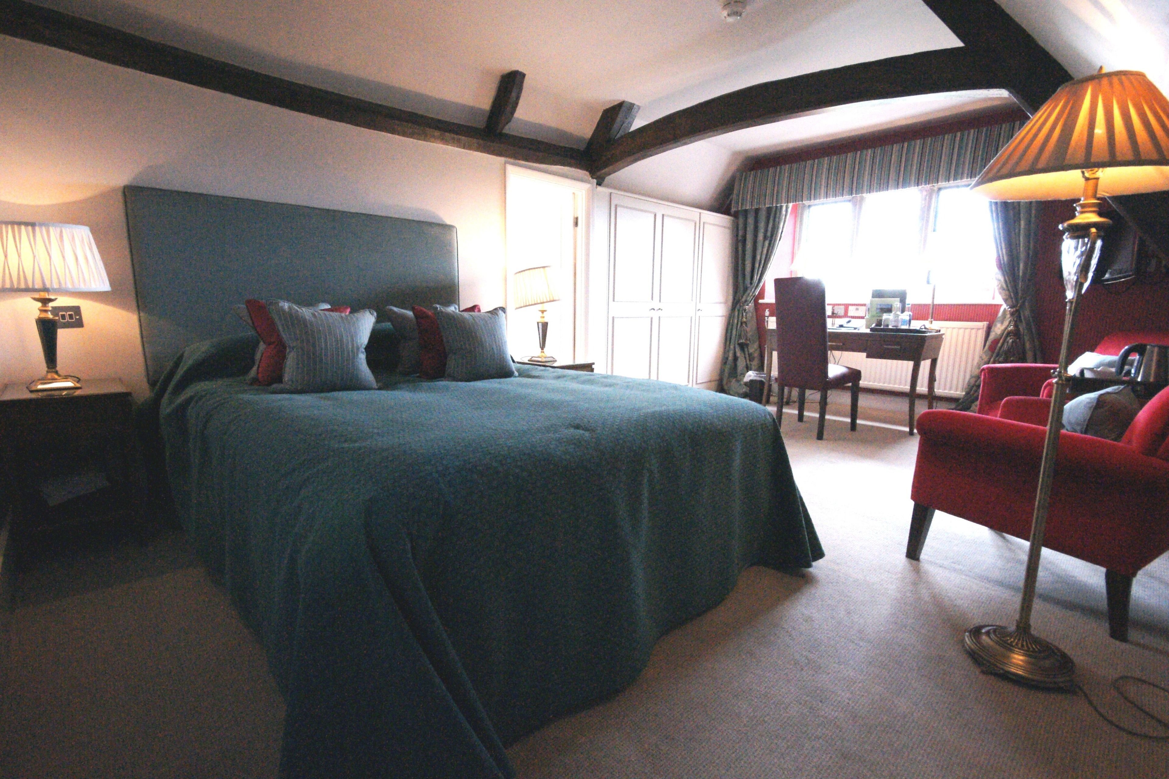 Una habitación de hotel con una cama grande, un escritorio, una silla y una lámpara.