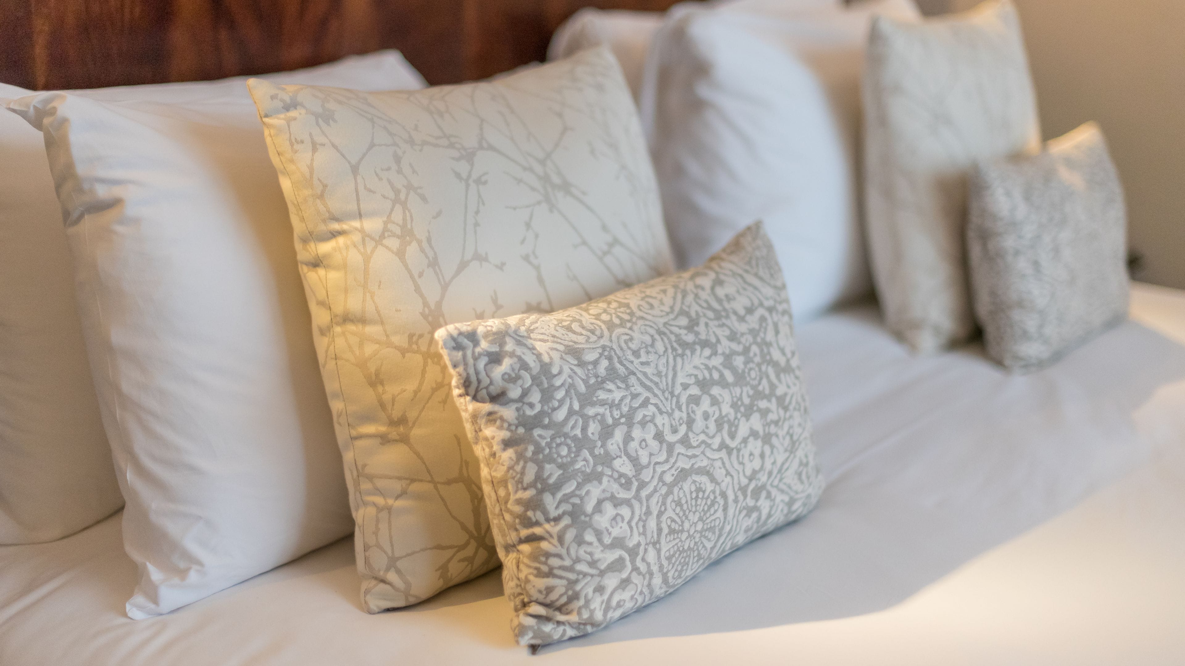 A bed with multiple pillows, some with patterns and others plain.
