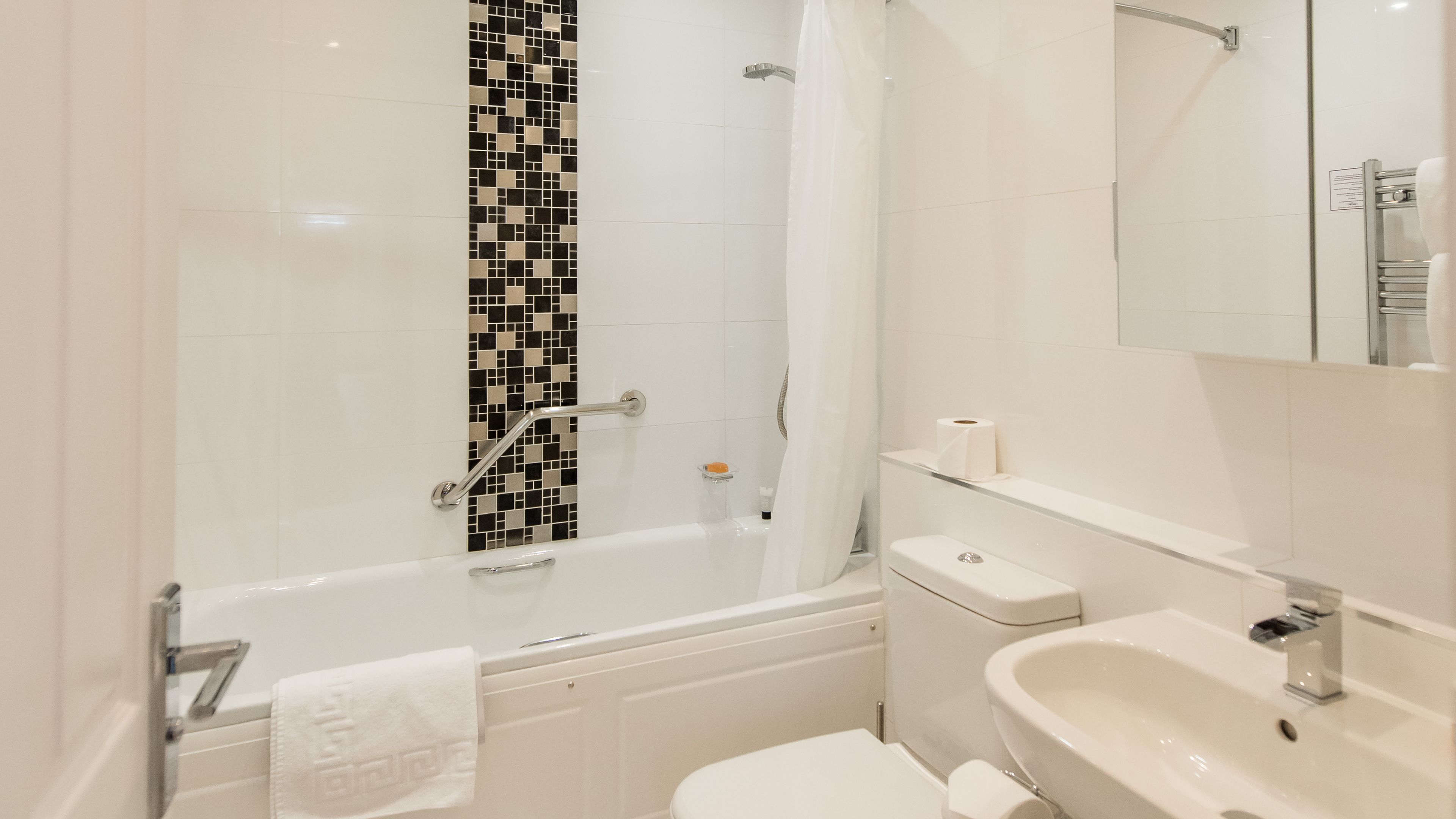 A modern bathroom with a bathtub, toilet, and sink.