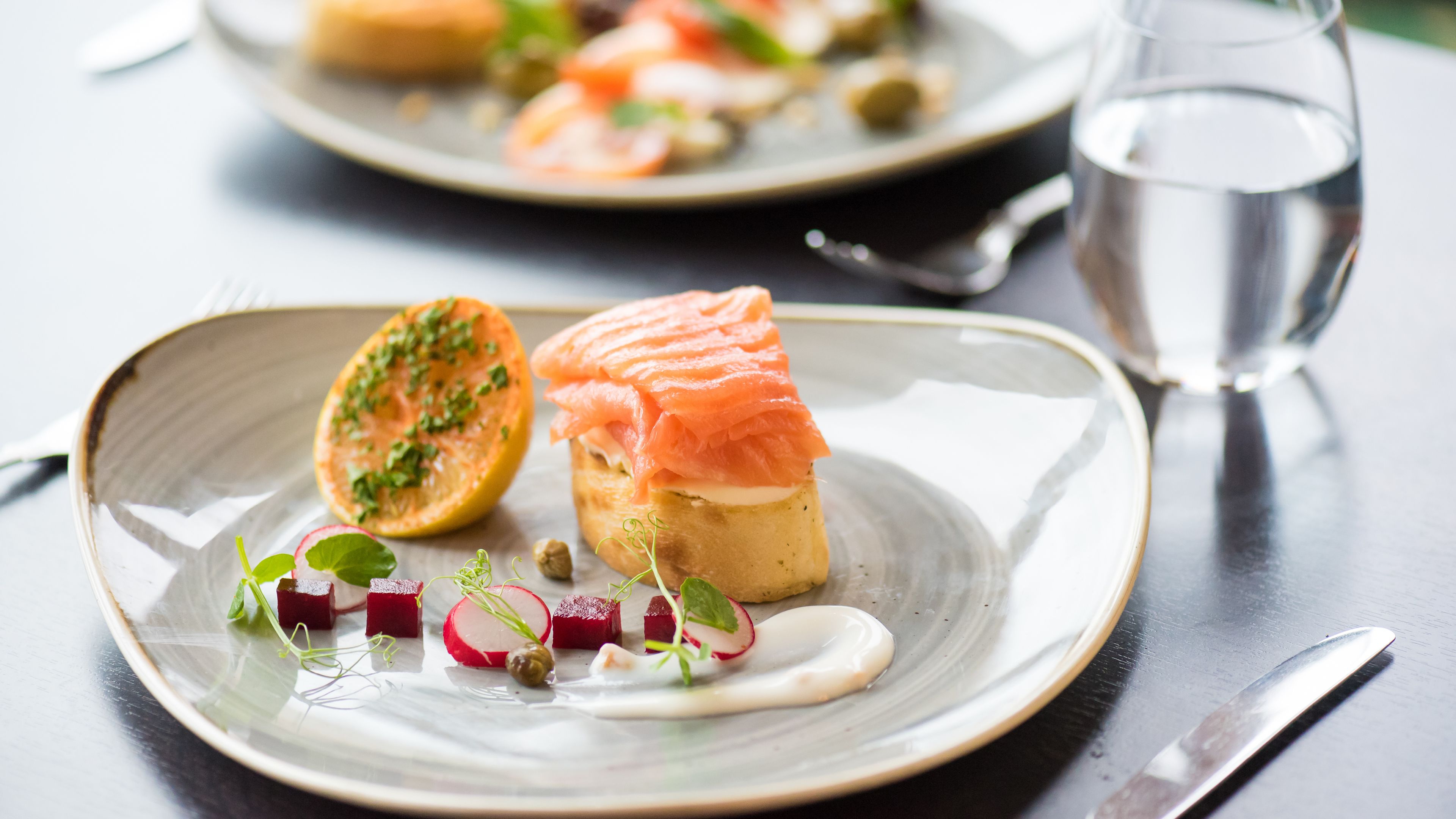 A plate with a salmon and beetroot dish, garnished with herbs and a sauce.