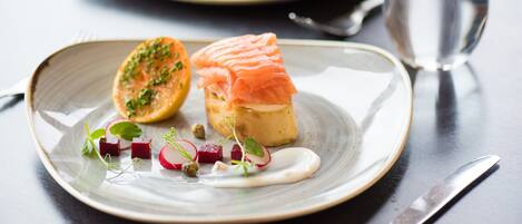 A plate with a salmon and beetroot dish, garnished with herbs and a sauce.