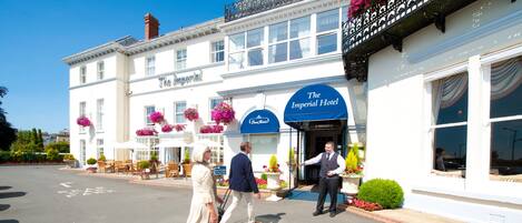 A hotel with a white facade, large windows, and a sign reading "The Imperial Hotel".