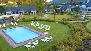 A resort with a swimming pool surrounded by lounge chairs and a well-maintained garden. - Knysna Hollow Country Estate (Knysna)