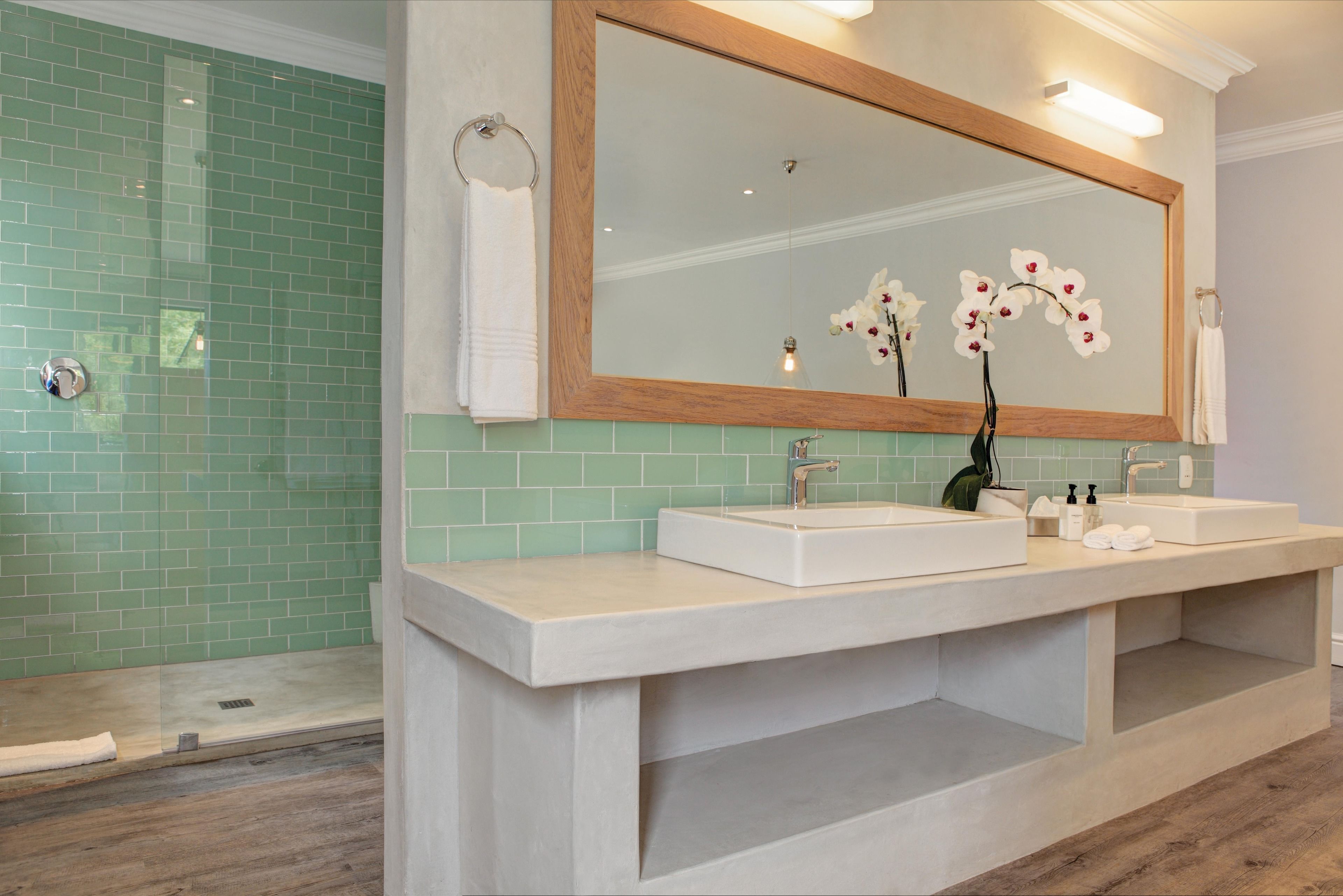 A bathroom with a large mirror, two sinks, and a shower area.