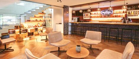 A modern bar area with wooden flooring, cushioned seating, and a well-stocked bar counter.