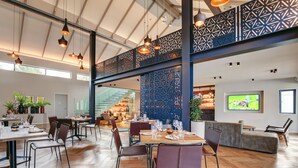 A spacious dining area with high ceilings, hanging pendant lights, and a modern geometric partition. - Knysna Hollow Country Estate (Knysna)