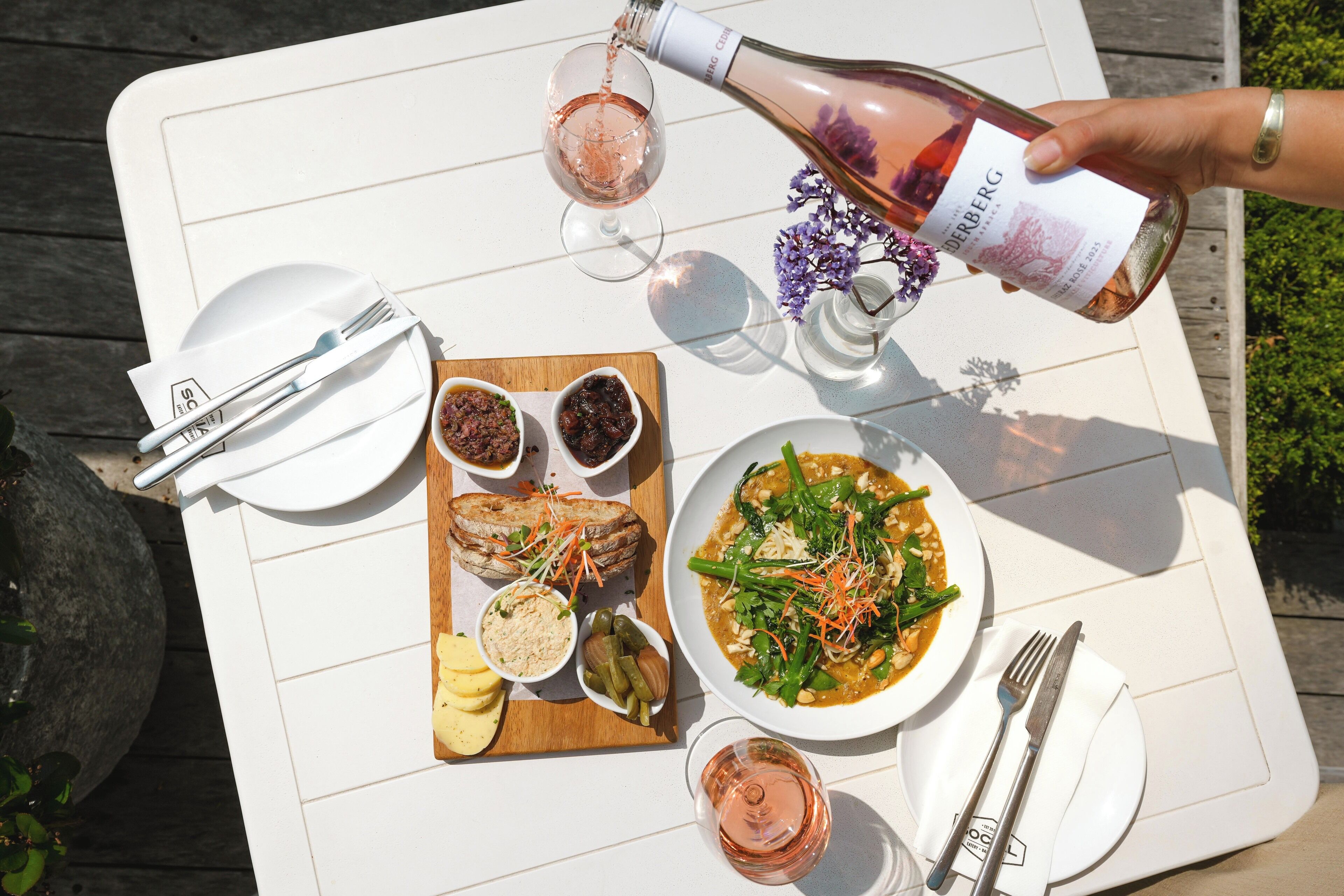 A table set with a meal, a bottle of wine, and a glass of wine being poured.