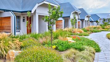 A row of modern houses with sloped roofs, surrounded by well-maintained gardens and a paved walkway.