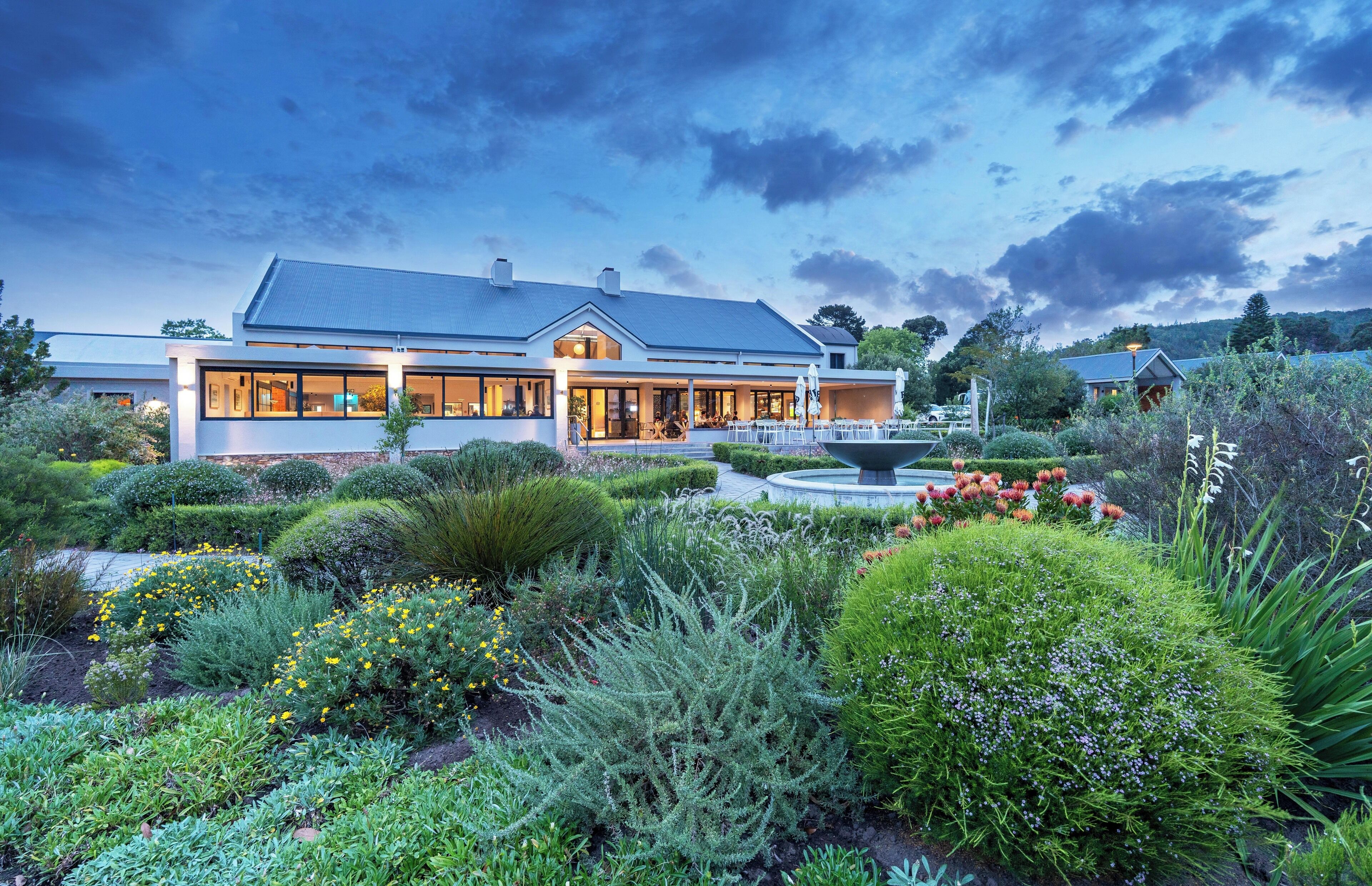 A modern house with a large garden, a fountain, and a well-maintained lawn.